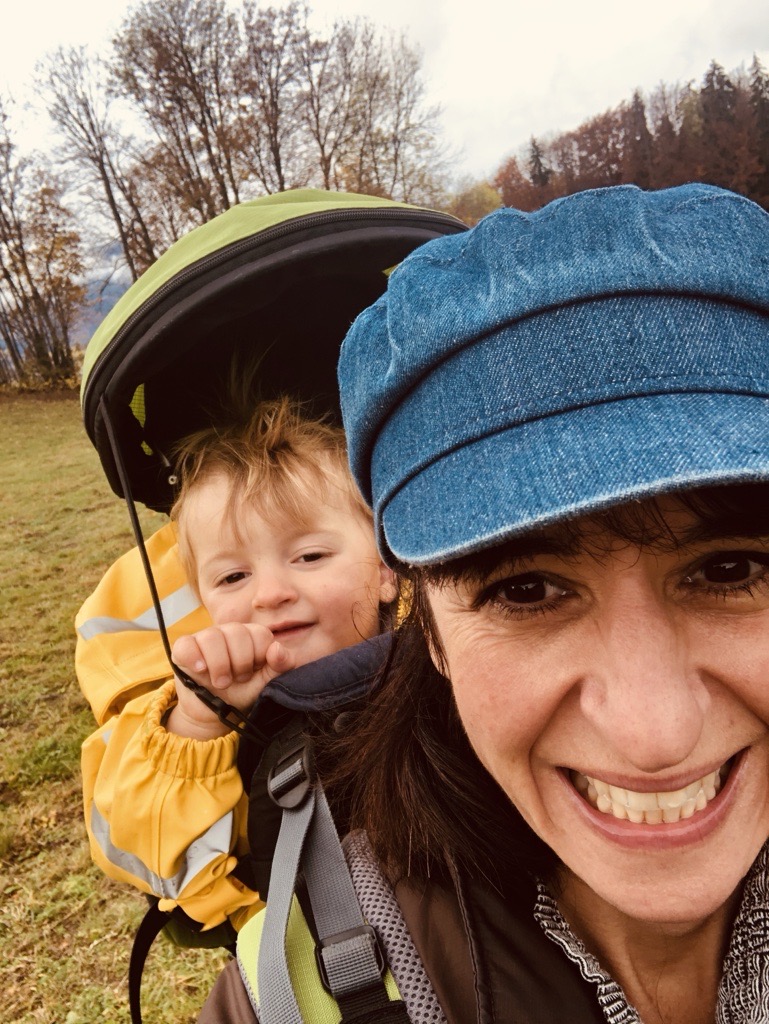 Rebecca hiking with her young son in a carrier, showing motherhood, connection to nature and an international family life.